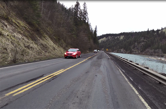Car drives on deteriorating pavement on US-12 between Big Canyon (Peck) and Orofino