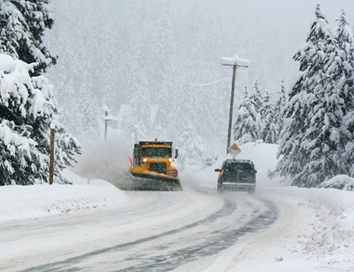 Winter weather scene with a snow plow clearing the road