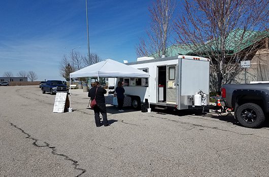 Customers line up six feet apart at a food truck stationed on I-84 at Blacks Creek