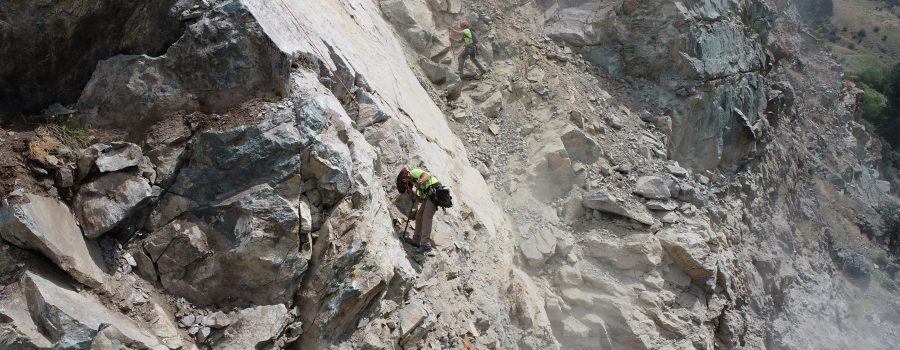 Rock scalers dislodge loose material on the slope above US-95 at milepost 188