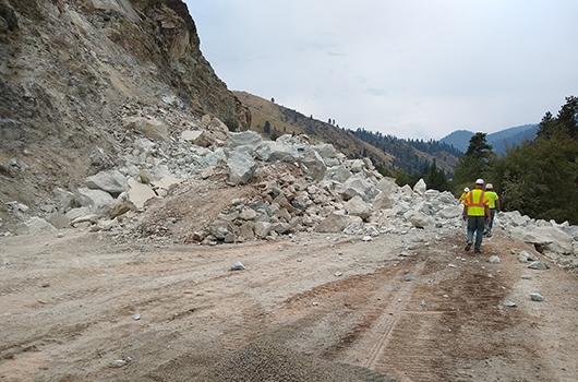 Workers walk through the shoofly on US-95 at milepost 188 after the biggest boulders were blasted