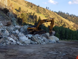 An excavator clears rock from the slide at MP 188 on US-95 near Riggins