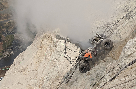 A driller works on the US-95 slide above MP 188