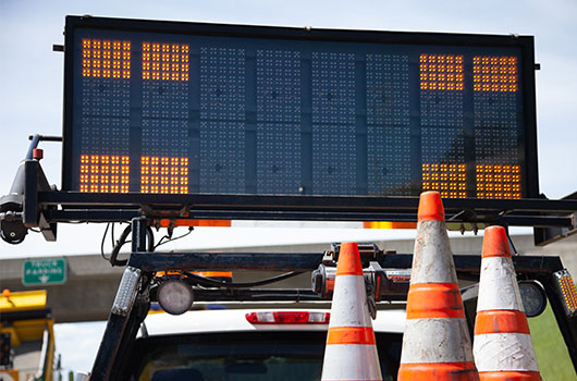 Image of sign in truck with cones in a work zone