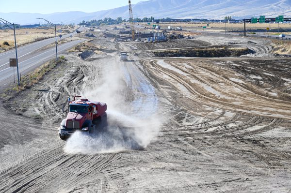 Water truck spraying dusty ground to control dust