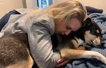 A woman hugs a dog.