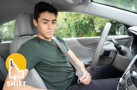 A young man buckling his seatbelt.