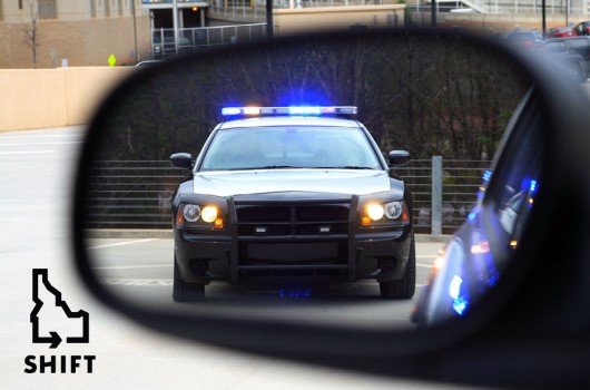 A police car seen from a vehicle's side mirror.