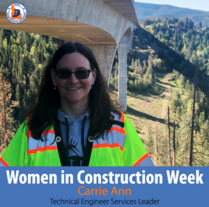 A woman in a safety vest under a bridge.