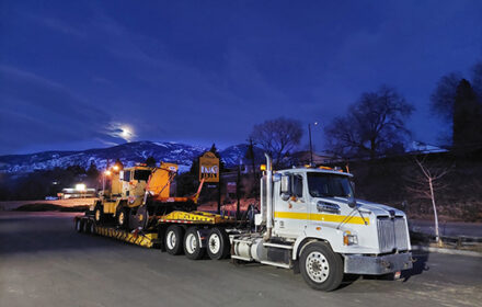 A semi truck hauling road equipment.