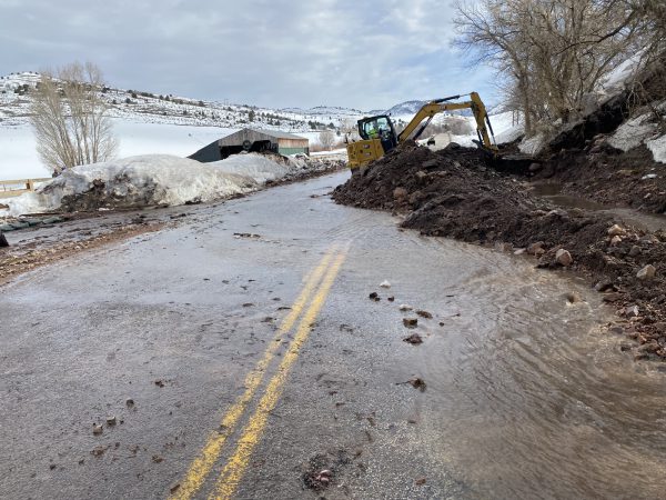 A backhoe works to remove mud from the roadway