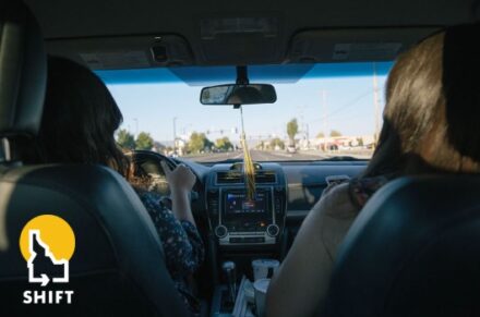 Two women in the front seats of a car, seen from behind.