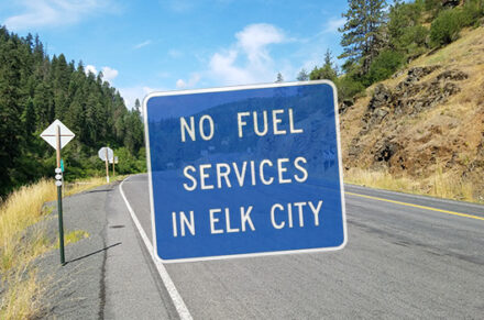 "No Fuel Services in Elk City" blue highway sign over a picture of SH-14.