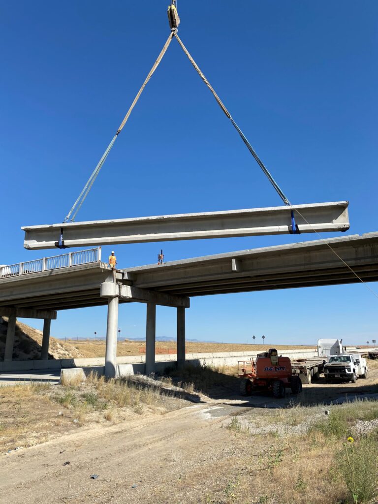A crane lifts a girder into the air.