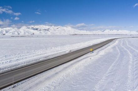 US-20 Aerial photo of long stretch of clear roadway with snow all around