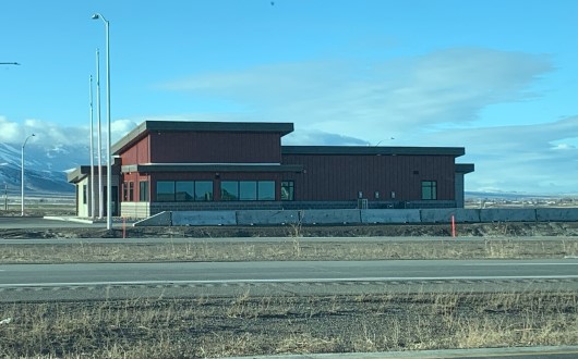 A red port of entry building seen from across the highway.