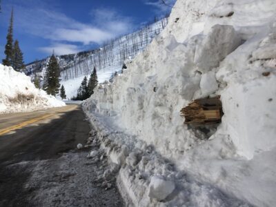 A broken tree trunk in a a pile of snow from an avalanche.