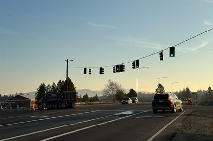 Sunset view behind intersection of SH-53 and Ramsey Road, showcasing temporary traffic signal overhead.