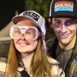 Man and woman at the fair testing out impairment simulation goggles.