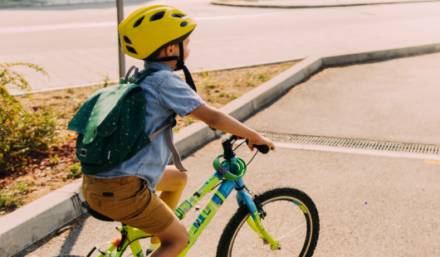 A boy on a bicycle wearing a yellow helmet.