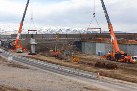 Two cranes lifting a girder.