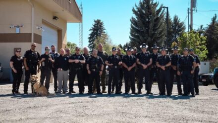 Many officers and a police k9 stand for a group photo.