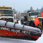 Two ITD snowplows. One has been digitally altered to say "Winning Name Here" on the front of the plow.