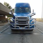 A semi truck with front license plate partially covered.