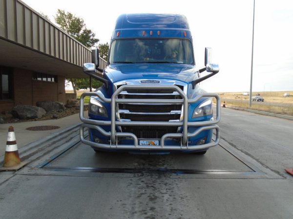 A semi truck with front license plate partially covered.