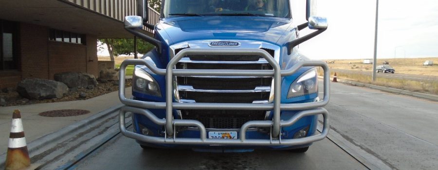 A semi truck with front license plate partially covered.