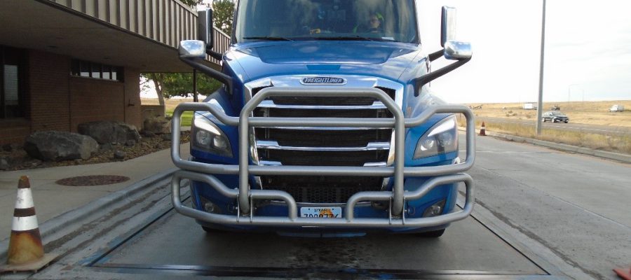 A semi truck with front license plate partially covered.