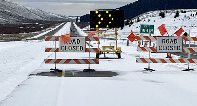 Snowy I-15 southbound roadway with road closure blockade signs and lights in place at Exit 184, Stoddard Creek.