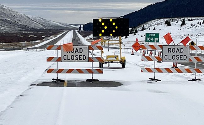 Snowy I-15 southbound roadway with road closure blockade signs and lights in place at Exit 184, Stoddard Creek.