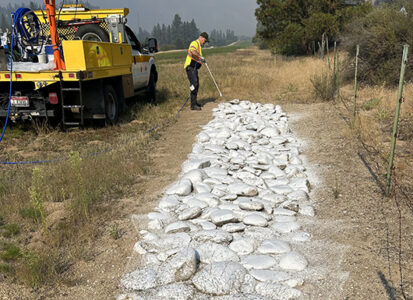 An employee paints the strip of rocks that serves as an airstrip marker.