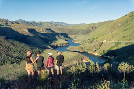 Four people with their backs to the camera look out at a scenic view of Black's Creek.