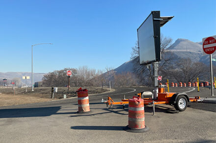 A digital message sign and construction barrels near the US-95 Aht'Wy Interchange project.
