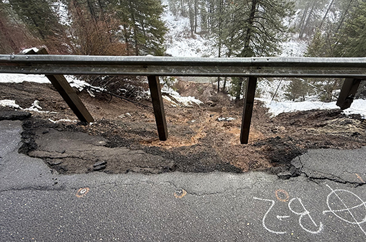 Guardrail hangs above a washed-out embankment