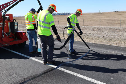 Employees crack sealing a road.