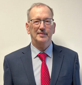 Paul Franz, wearing a blue suit and red tie.