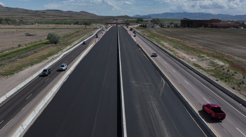 Drone photo of I-15 with live traffic and the Fort Hall Interchange in the background.