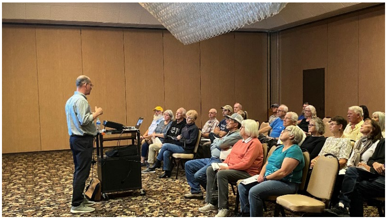 A group listens to a presentation being given as part of a public meeting concerning the I-15/ US-20 project in Idaho Falls. 