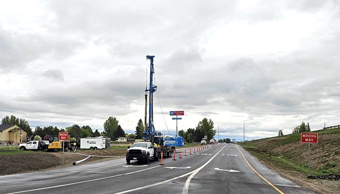 A drill rig and other equipment, as well as orange traffic control devices, at US-20 Exit 333 while work is being conducted.