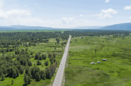Two-lane highway stretches through green meadow