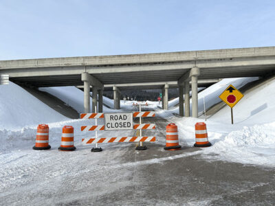 I-15 Stoddard Creek Exit 184 snowy photo taken from under the overpass bridge of barriers closing the road that passes below.