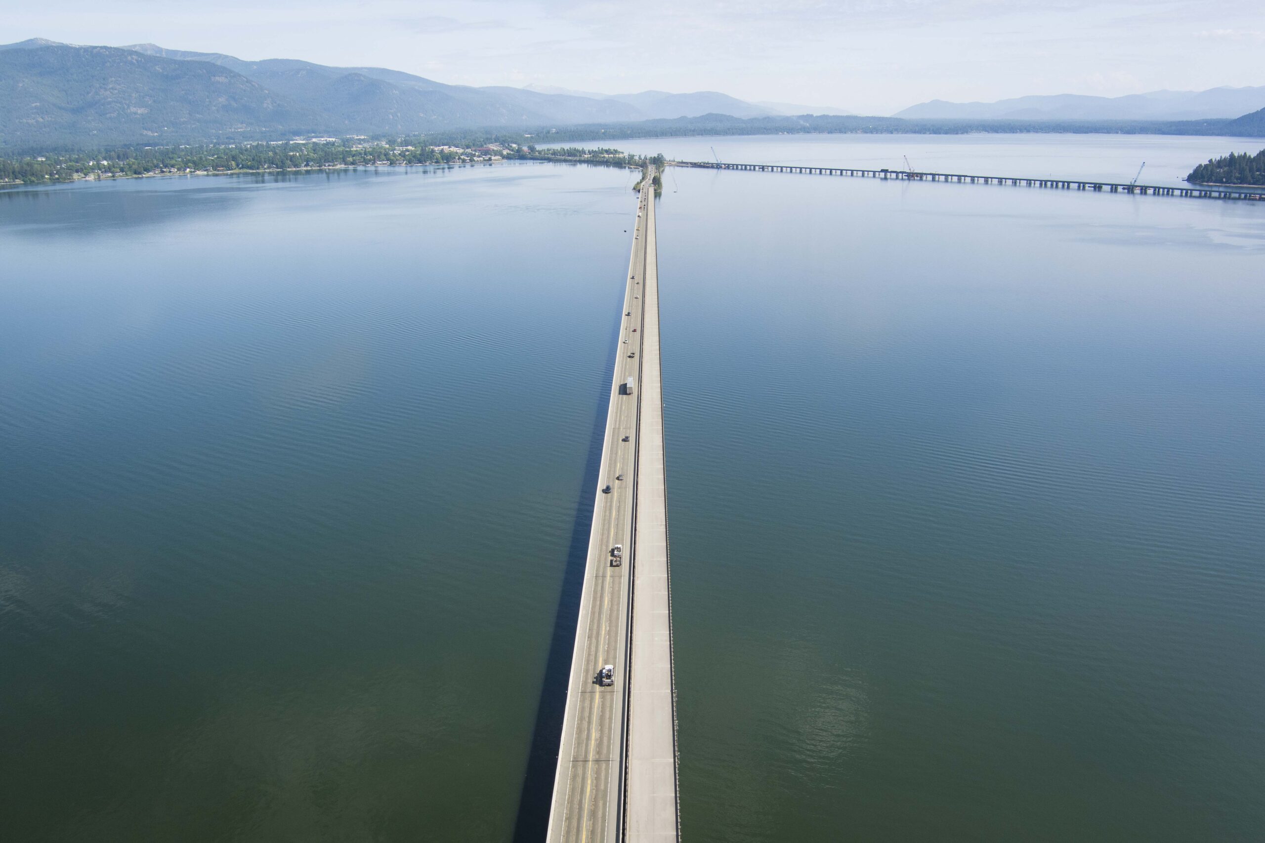 Aerial view of a long bridge stretching across a lake towards land.