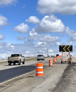 US-20 paving work Spring 2025 showing a sign directing drivers to change lanes preceding the work zone