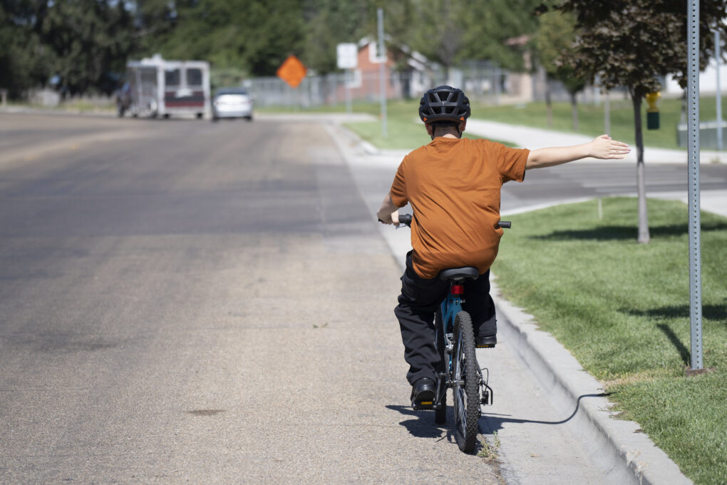 A boy on a bike signals a right turn.