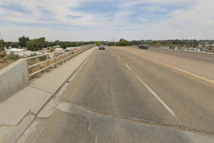 Bridge over freeway with a couple of cars going across.