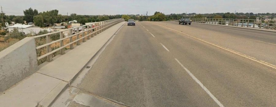 Bridge over freeway with a couple of cars going across.