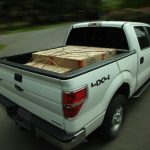 White truck with a secured load in the truck bed.